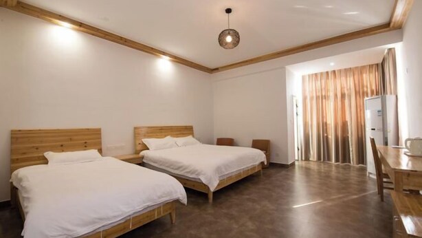 A room with two wooden beds, a wooden table, and a ceiling light fixture.