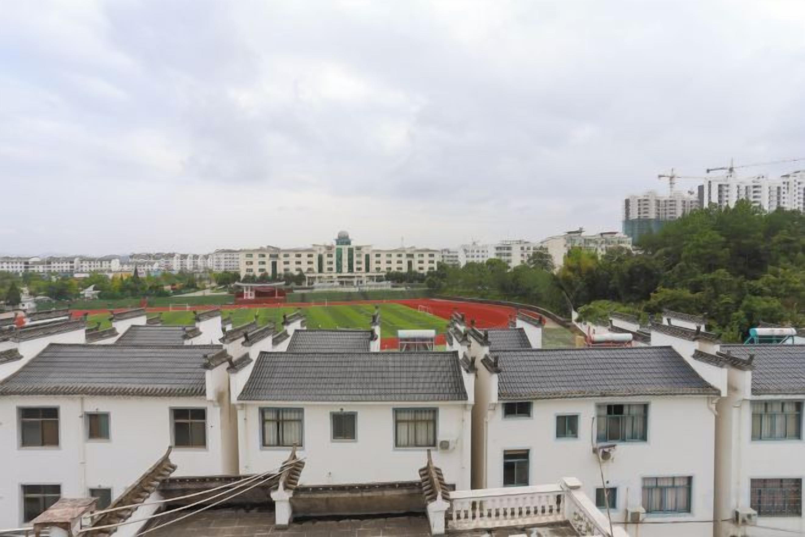 Zona residencial com arquitetura tradicional, campo esportivo e edifícios modernos ao fundo.