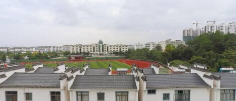 Zona residencial com arquitetura tradicional, campo esportivo e edifícios modernos ao fundo.