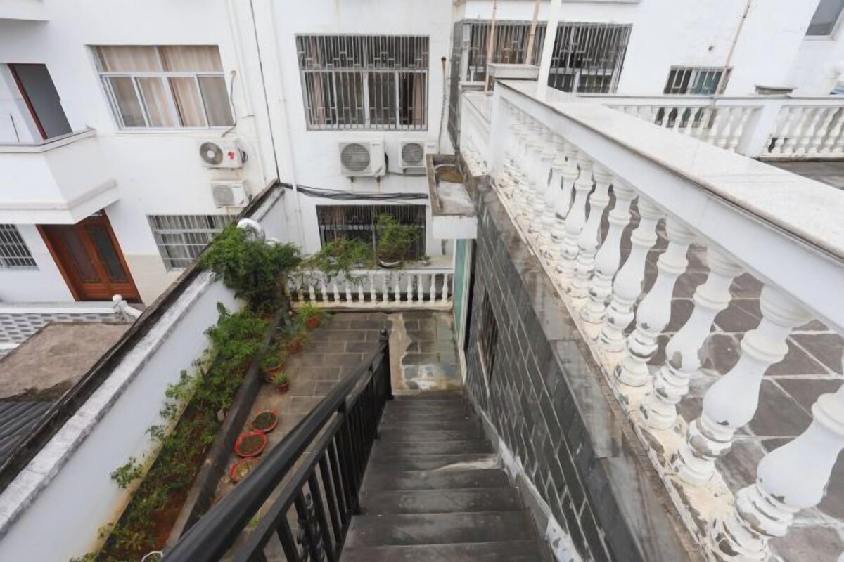 A multi-level residential building with a staircase, air conditioning units, and a white balustrade.