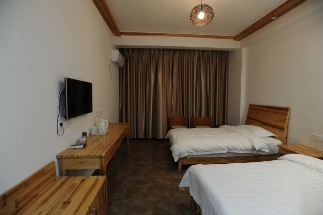 Una habitación de hotel con dos camas, un escritorio de madera, un televisor y un fondo de cortina.