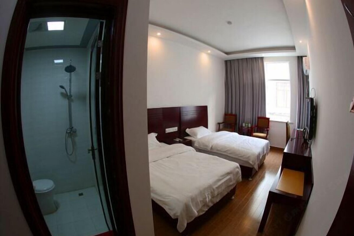 A hotel room with two beds, a shower, a desk, and a TV.