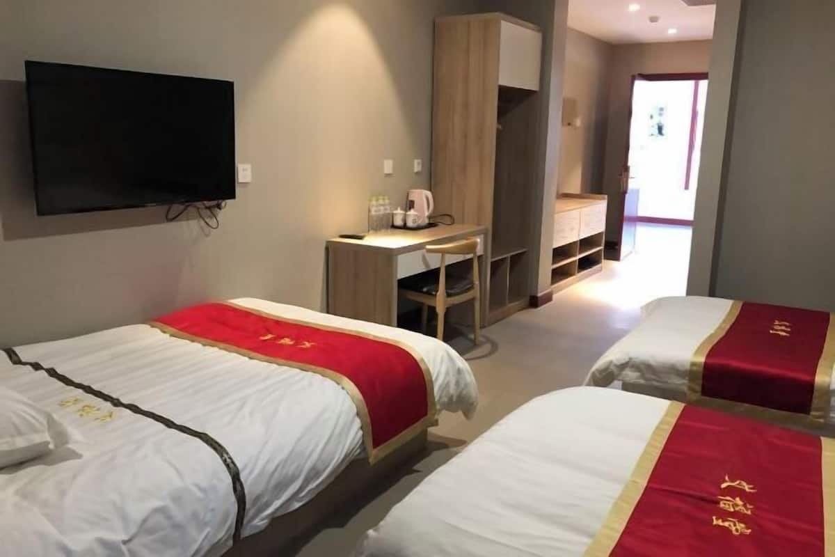 Ein Hotelzimmer mit zwei Betten, einem Fernseher, einem Schreibtisch und einem Kleiderschrank.