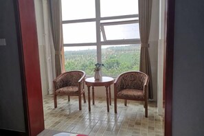 Een kamer met een groot raam, twee gestreepe stoelen, een tafeltje en een vaas.