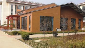 A modern building with a flat roof, large windows, and a well-maintained garden area.