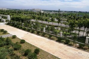 An aerial view of a landscaped area with pathways, greenery, and distant buildings.