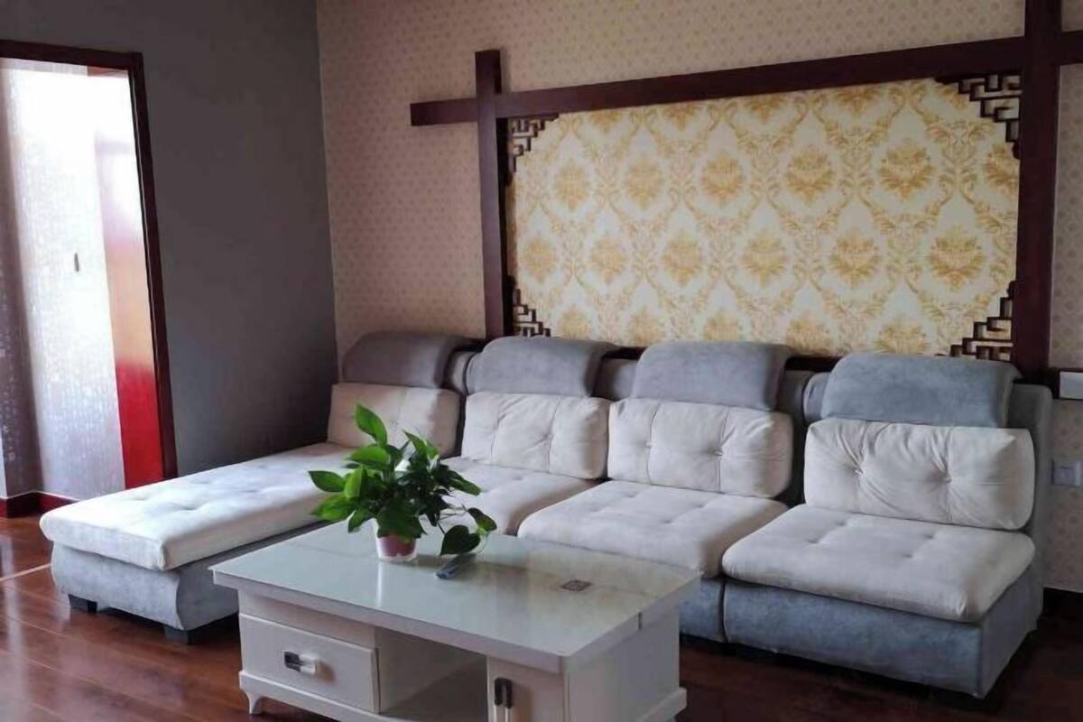 Ein modernes Wohnzimmer mit einem Ecksofa, einem Glastisch und einer Topfpflanze.