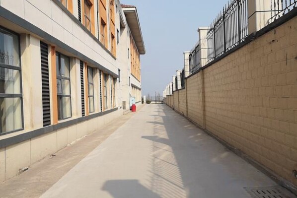 A corridor with a brick wall on one side and a building with windows on the other. - Aifutang Grand Hotel (Weifang)