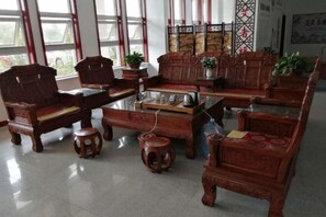 A traditional wooden furniture arrangement with a glass-top coffee table, multiple chairs, and stools. - Aifutang Grand Hotel (Weifang)