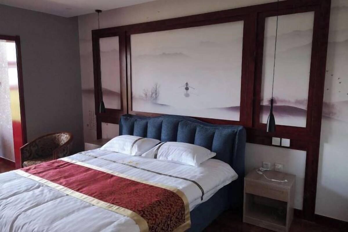 Ein Schlafzimmer mit einem Bett, einem Nachttisch, einem Sessel und einem großen Wandbild.