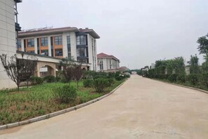 A residential street with modern houses, a clear sky, and a well-maintained sidewalk. - Aifutang Grand Hotel (Weifang)