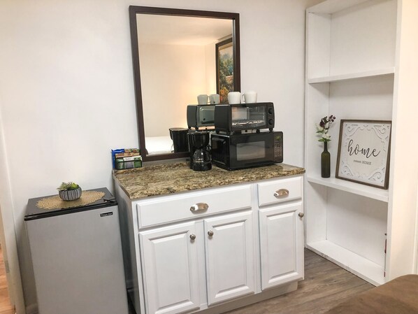A kitchenette with a coffee maker, microwave, and small refrigerator.