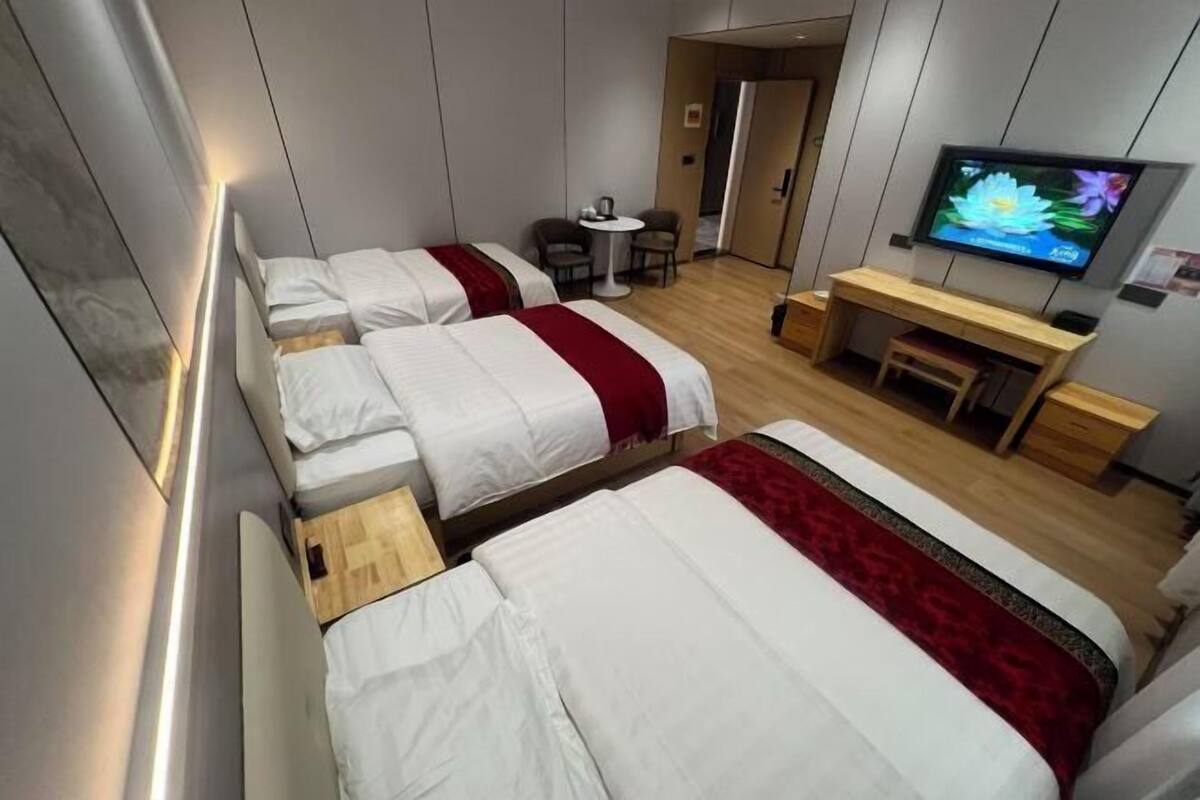 A hotel room with two beds, a desk, a TV, and a small table.
