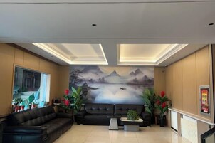 Un vestíbulo moderno con un sofá de cuero negro, una mesa de centro y un mural de un paisaje montañoso.