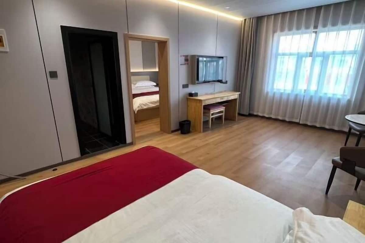 A hotel room with a bed, a desk, a TV, and a window with curtains.