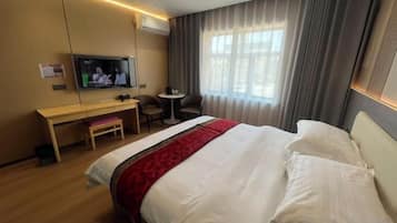 A hotel room with a bed, a desk, a television, and a window with curtains.