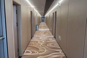 Un pasillo de hotel con alfombra estampada, puertas a ambos lados y un cartel indicando una dirección.