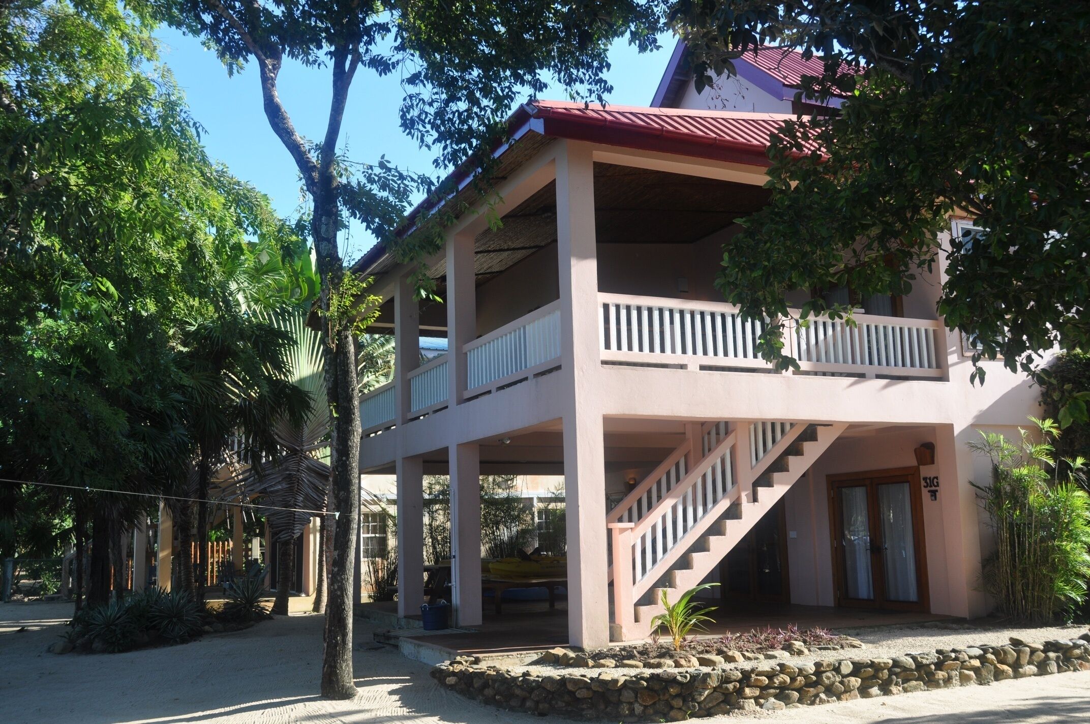 Un bâtiment à deux étages, avec un toit rouge, un balcon à l’étage supérieur et un escalier menant à l’entrée.