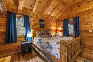A wooden cabin bedroom with a bed, two nightstands, a window, and a sign on the wall. - Cozy & Romantic cabin in Hocking Hills (Logan)