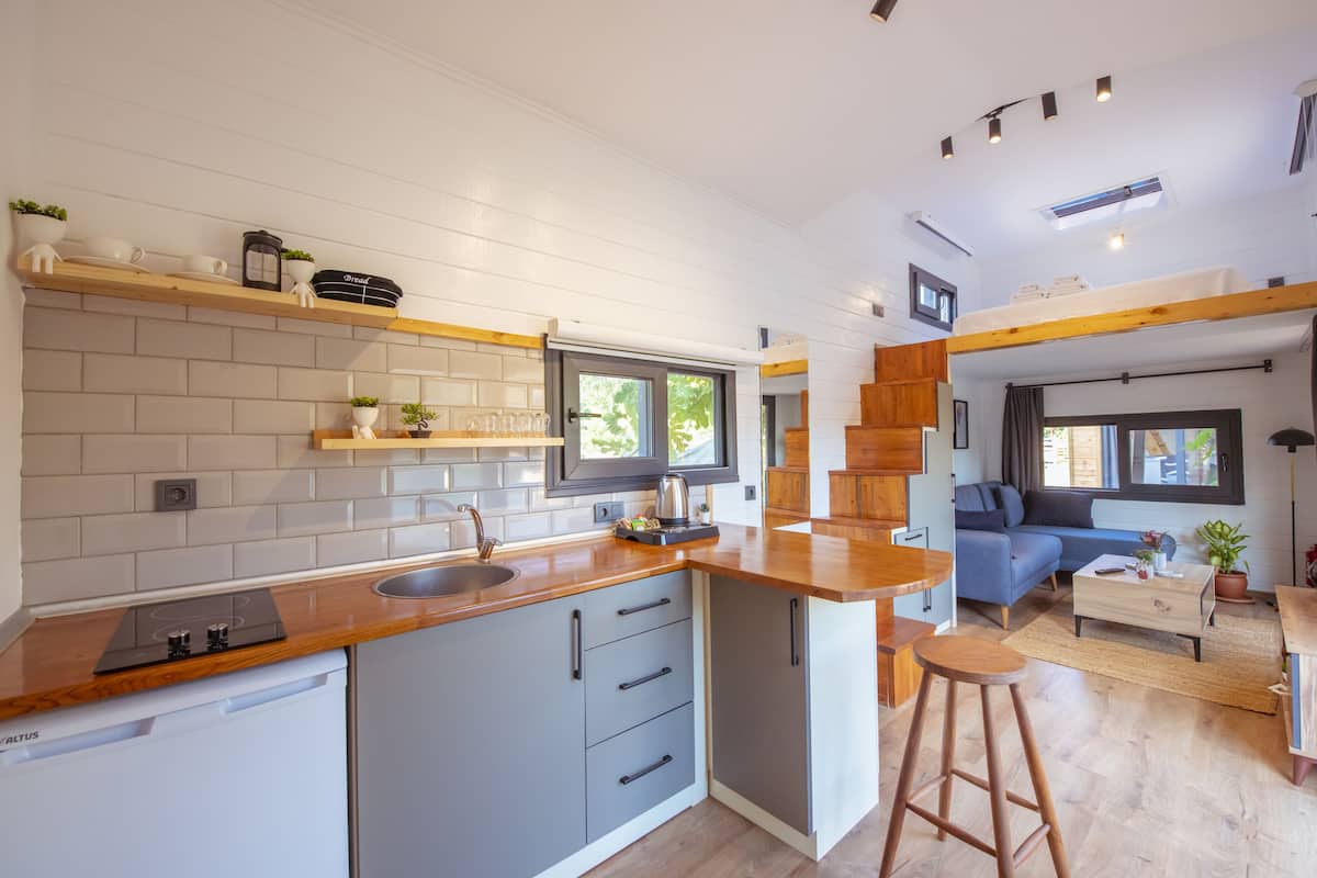 A modern kitchen with a built-in stove, grey cabinets, and wooden countertops.