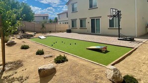 A residential backyard with a lawn, a basketball hoop, and a sandbox.