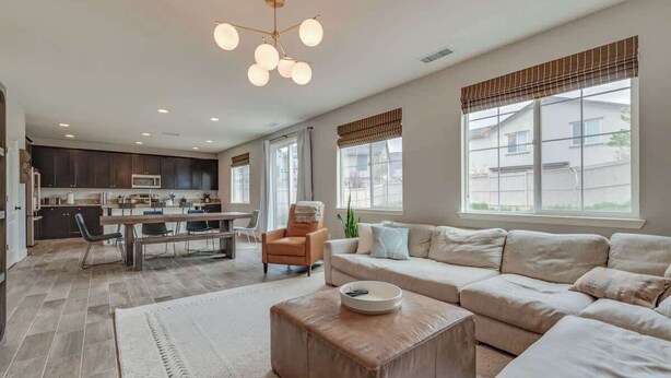 A modern living room with a sofa, ottoman, and dining area.