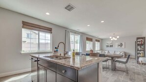 A spacious kitchen with a large island, a dining area with a sofa, and a view of the outside.