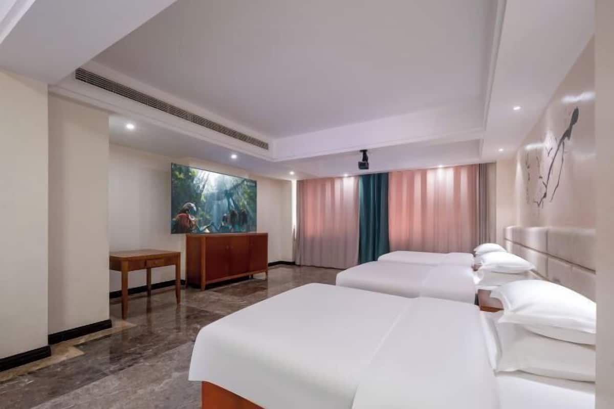 A hotel room with two beds, a desk, a television, and a painting on the wall.