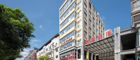 A multi-story building with commercial signage, a covered entrance, and a staircase leading to an upper level.