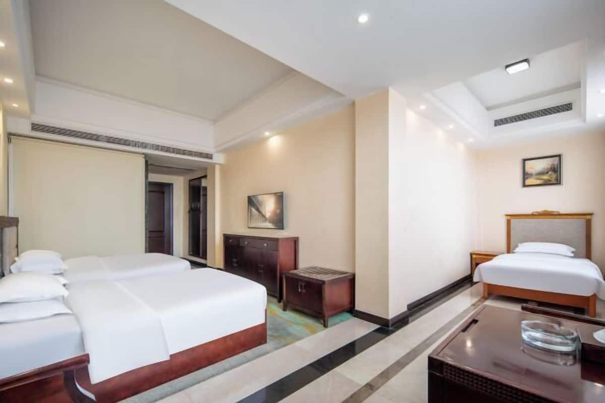 A hotel room with two beds, a desk, a cabinet, and a painting on the wall.