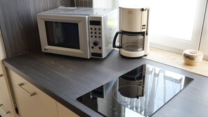 Una cocina moderna equipada con microondas, cafetera y placa de inducción.