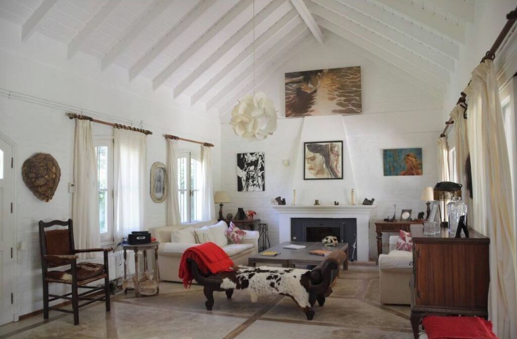 A spacious living room with a fireplace, a cow sculpture, and various artworks on the walls.