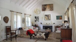 Ein geräumiges Wohnzimmer mit Kamin, einer Kuhskulptur und verschiedenen Kunstwerken an den Wänden.