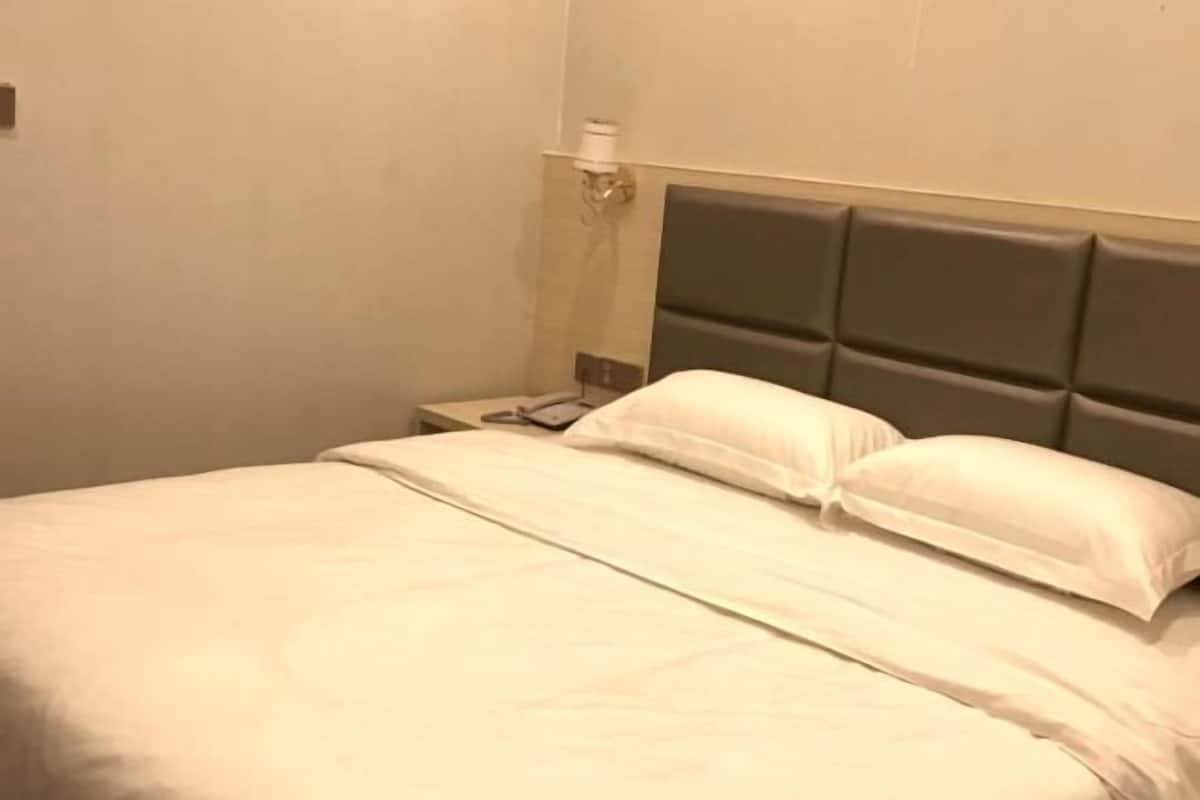 A hotel room with a bed, a nightstand, and a lamp.