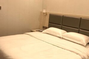 Una habitación de hotel con una cama, una mesita de noche y una lámpara.