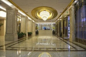 A hotel lobby with a reception desk, marble flooring, and a large chandelier. - Xinfeng Yingbinguan (Xinfeng)