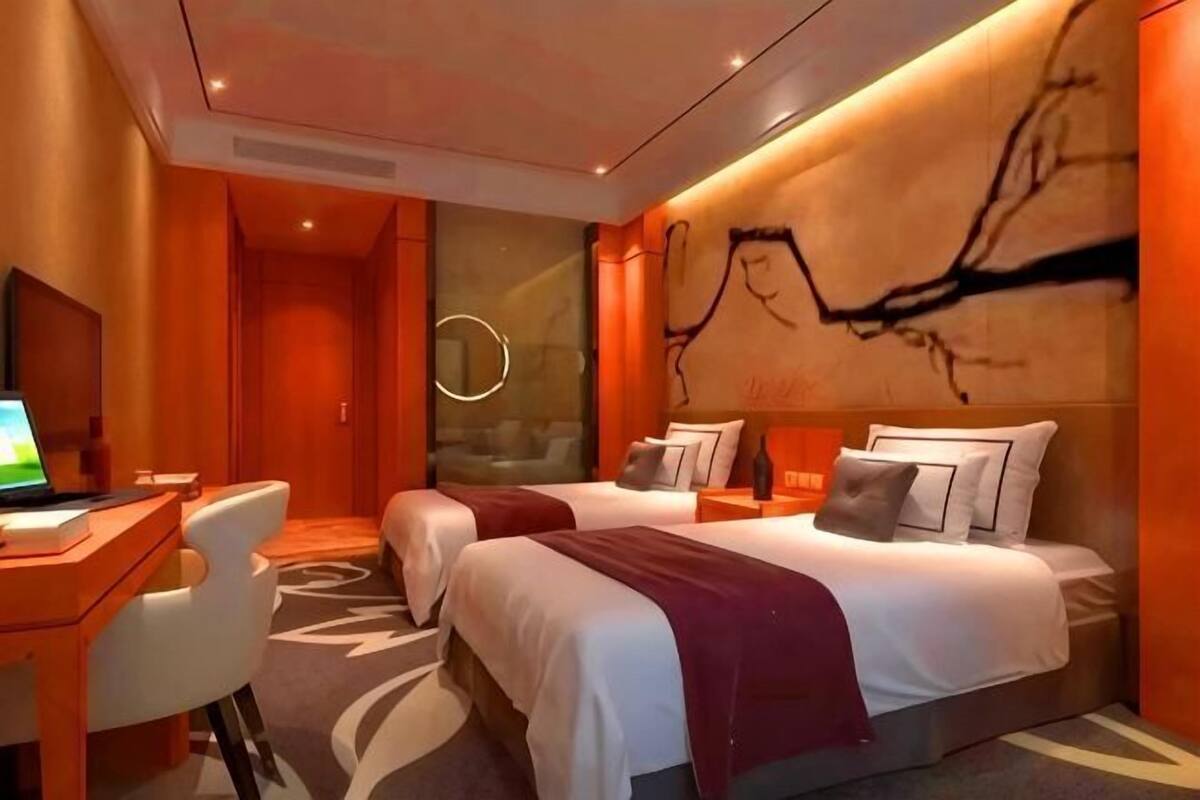 A modern hotel room with a large bed, a desk, and a seating area.