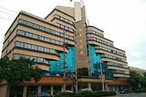 A multi-story building with a prominent vertical sign, multiple windows, and a reflective glass facade. - Xinfeng Yingbinguan (Xinfeng)