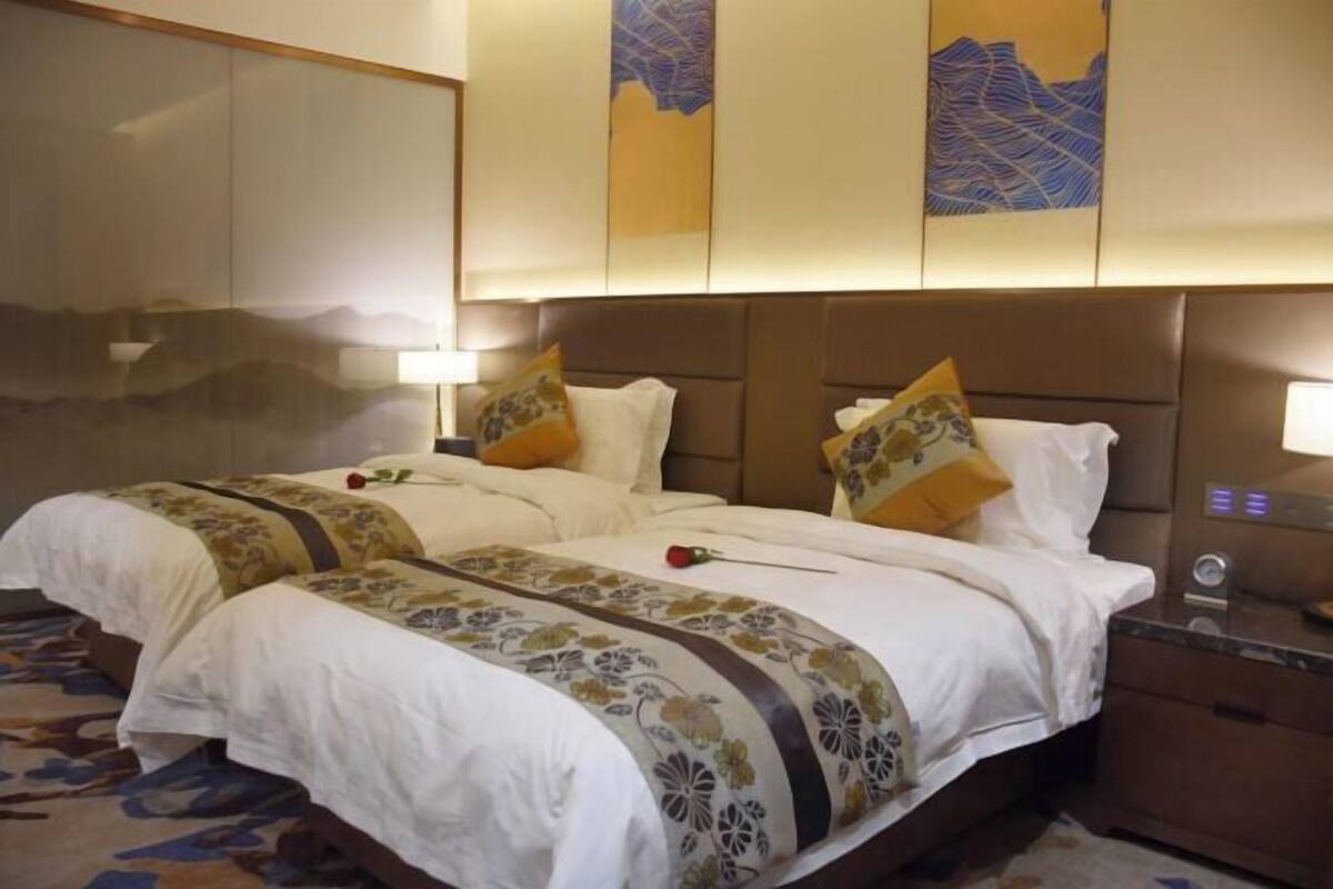 Una habitación de hotel con dos camas, un espejo grande y obras de arte en la pared.