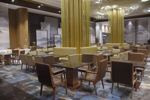 Un comedor de hotel con varias mesas y sillas, techos altos y columnas decorativas.
