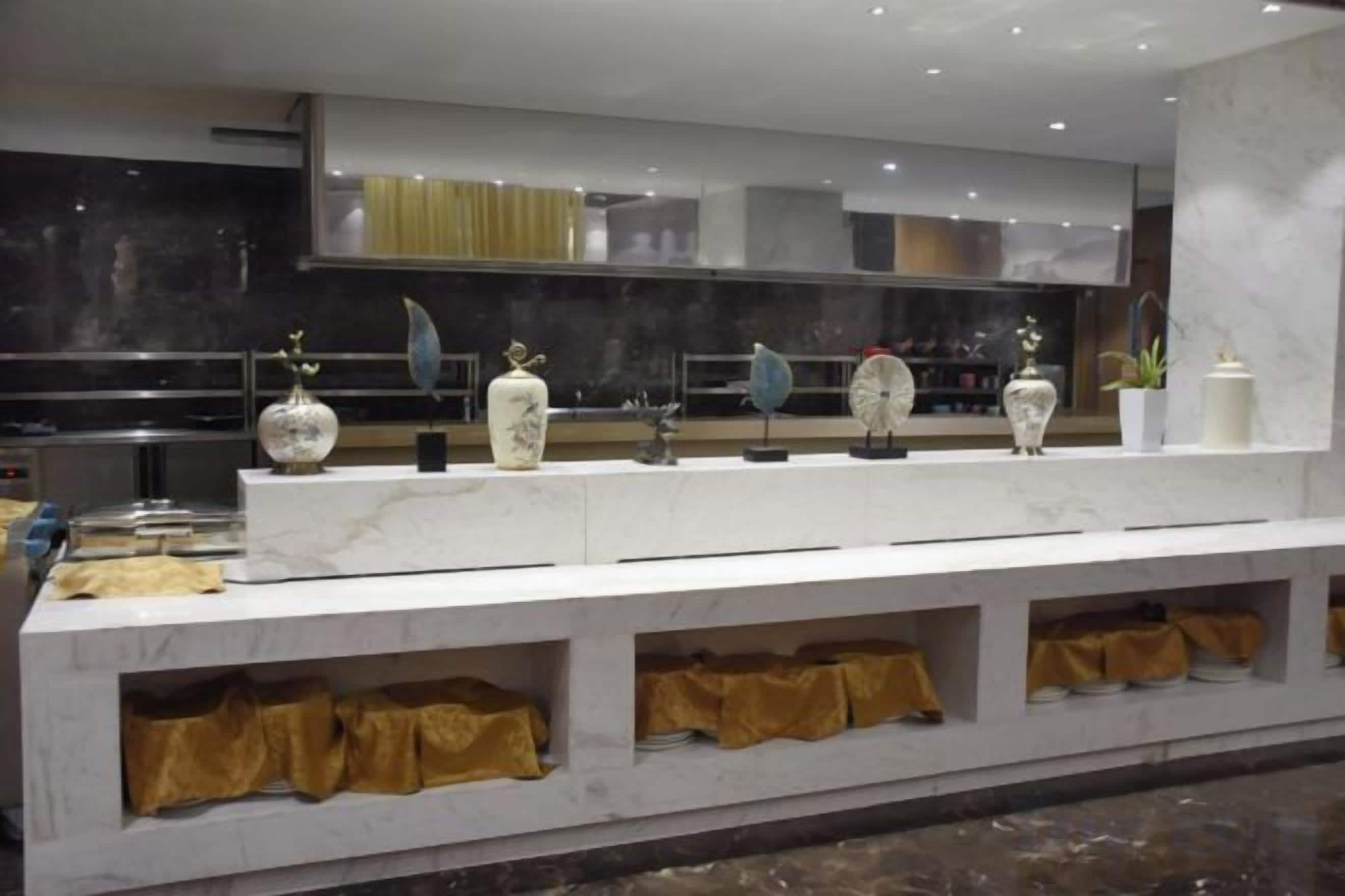 Una encimera de mármol con jarrones decorativos y una cocina moderna al fondo.