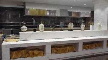 Una encimera de mármol con jarrones decorativos y una cocina moderna al fondo.