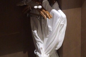 A white garment hanging on a wooden hanger in a dimly lit room. - Luxinan Hot Spring Hotel (Heze)