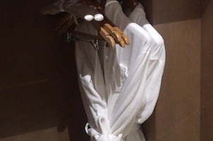 Una prenda blanca colgada en una percha de madera en una habitación con poca luz.