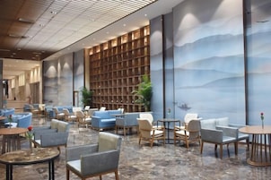 A spacious lobby with seating areas, a large bookshelf, and a mural of a mountainous landscape.