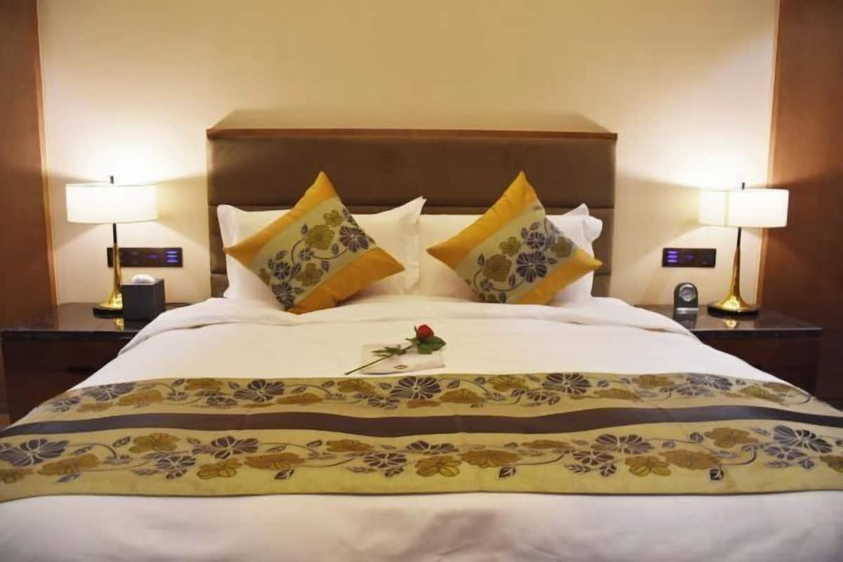 Una cama bien hecha con almohadas estampadas con motivos florales y una colcha decorativa.