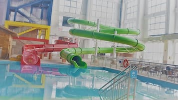 An indoor swimming pool with multiple slides and a diving platform.