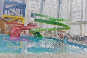 Una piscina interior con varias toboganes y una plataforma de clavados.