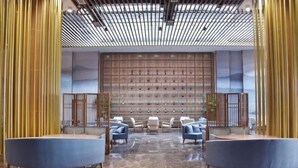 Eine großzügige Lobby mit Marmorboden, Sitzgelegenheiten inklusive Sofas und Sesseln, einer Wand mit gerahmten Bildern und einer Decke mit Gittermuster.