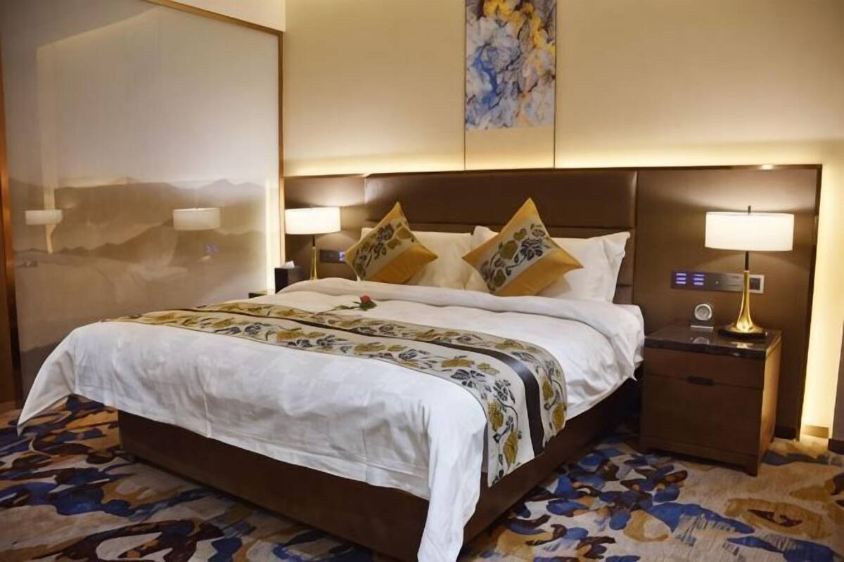 Una habitación de hotel con una cama grande, dos mesitas de noche y un cuadro en la pared.